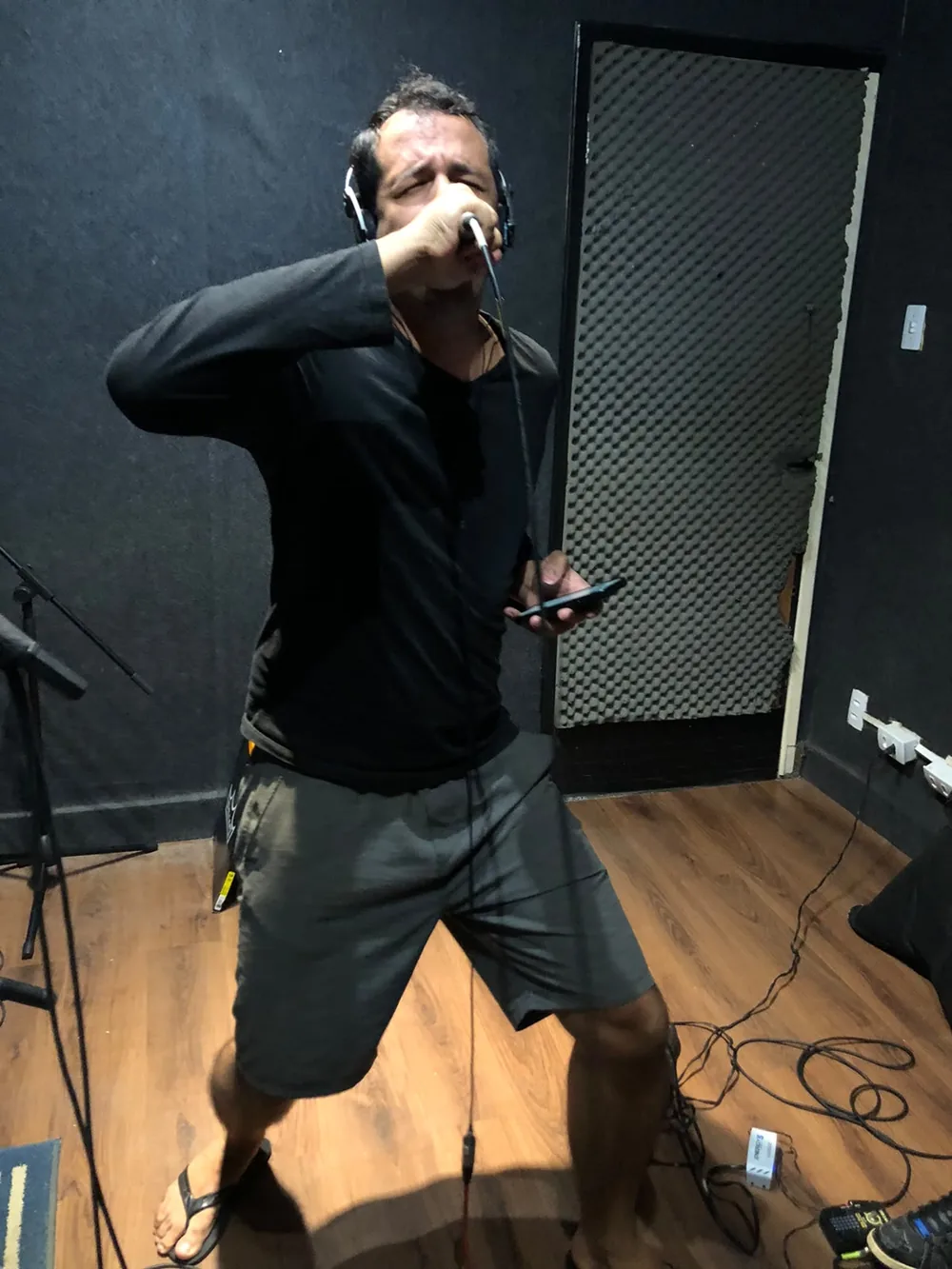 Estúdio: vocalista cantando ao microfone, de fones de ouvido